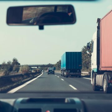 shows a view of a car in a highway with trucks, learn What to do immediately after a truck accident