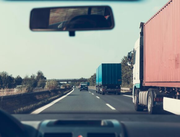 shows a view of a car in a highway with trucks, learn What to do immediately after a truck accident