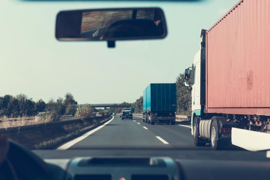 shows a view of a car in a highway with trucks, learn What to do immediately after a truck accident